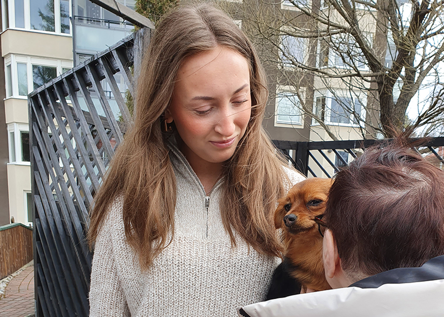 En ung flicka klappar en liten hund.