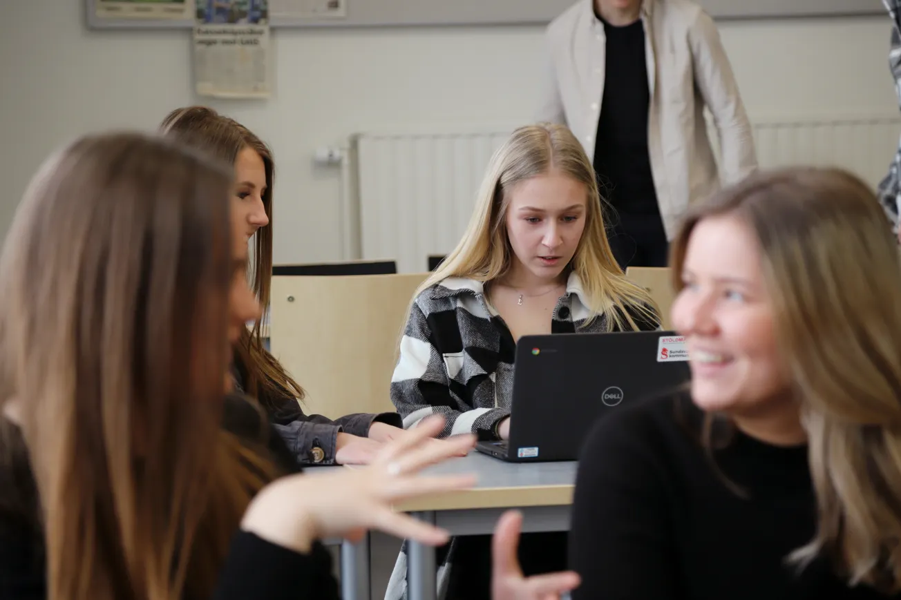 En grupp unga kvinnor sitter runt en bärbar dator.