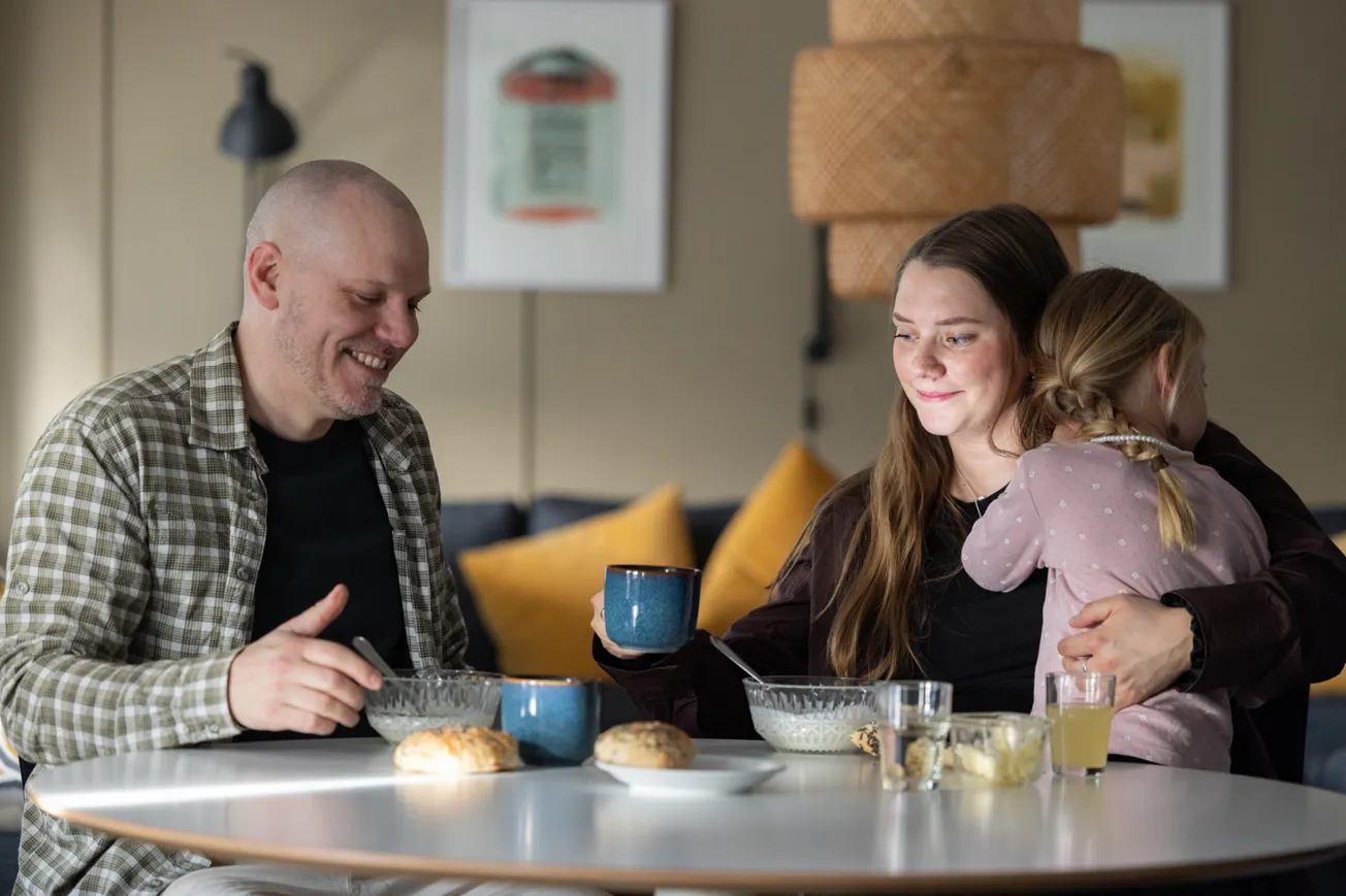 Två vuxna och ett barn sitter vid frukostbordet.